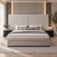 A modern upholstered bed with a tall geometric headboard and matching footboard, shown in a styled bedroom setting with neutral bedding, side tables, lamps, and warm ambient lighting.