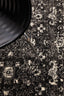 Detailed view of charcoal rug pattern beneath modern black chair.