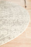 Curved edge of round white silver rug on wooden floor