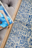 Detailed view of navy rug pattern beside grey tufted sofa, showing elegant woven texture.