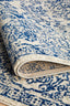 Folded rug edge highlighting navy floral designs, thick pile, and durable woven backing.
