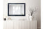 Silver French provincial ornate mirror styled on dark wall with chandelier and modern armchair.