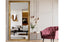 Gold French provincial ornate mirror styled in lounge with pink velvet chair and wall décor.
