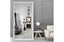 White French provincial ornate mirror styled in living room with chandelier and grey walls.