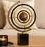 A sphere with concentric gold rings on a black base in a home setting