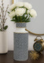 Decorative vase with white flowers on a table next to a clock and another vase.