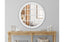White Hampton's round window mirror styled above wooden console in elegant hallway.