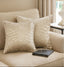 Beige pillows with patterns on a couch with a book and glasses in a living room setting