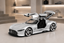 A silver Mercedes-Benz Vision GT concept car model with open butterfly doors, displayed on a light-colored surface in a modern, softly lit interior setting.