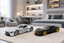 Two Mercedes-Benz sports cars, one silver and one black with yellow wheels, displayed on a light beige rug in a modern, well-lit bedroom setting.