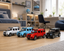 Four toy Mercedes-Benz G-Class SUVs in white, light blue, red, and black are lined up on a light wood floor in a modern, well-lit child's bedroom.