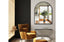 Small black metal arch mirror styled above console with mustard chair