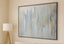 Abstract painting with blue and gold tones on a wall in a room with a lamp and bed.