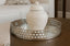 Decorative white jar on a mirrored round tray with a patterned background
