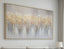 Abstract painting with gold and gray tones on a wall above a sofa.