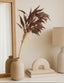 Decorative elements including a vase with dried plants, a lamp, and a small arch-shaped object on a shelf.