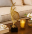 Decorative gold sculpture on a table with a candle and orchids in the background
