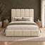 A modern upholstered bed with a tall segmented headboard and matching footboard in a warm cream tone, styled in a bedroom with neutral bedding, side tables, plants, and a textured wall.