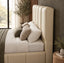 A beige upholstered bed frame with a tall, channel-tufted headboard and matching footboard, styled with white and beige bedding, textured pillows, and a green throw blanket in a modern bedroom setting.
