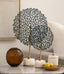 Decorative metal tree sculpture on a table with candles and a vase.