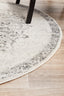 Edge detail of round silver rug with subtle grey border on a wooden floor.