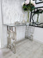 Royale console table with silver frame and clear glass top styled with flowers and décor.