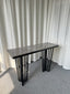 Serena console table with black metal frame and grey marble top in studio setting.