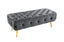 Dark Grey Shirley Ottoman featuring a sturdy gold frame and tufted velvet cushioned top.