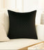 Black textured pillow on a beige sofa with a white wall background