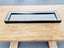 Modern black beaded mirror tray on wooden table – elegant & stylish.