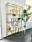 Nelson Bookcase in polished gold finish styled with decorative vases, photo frames, and greenery – side view highlighting its geometric structure and modern design.